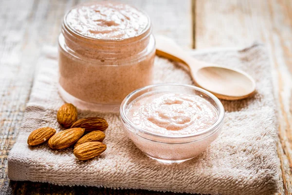 Spa concept with almond nuts and scrub on wooden background — Stock Photo, Image