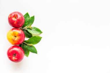 Mutfak masasında yeşil yapraklı kırmızı elmaların üst görüntüsü