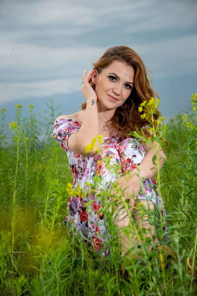 Kobieta Kwiatowej Sukience Siedzi Zielonym Polu — Zdjęcie stockowe