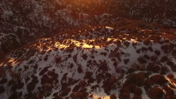 夕阳西下冬雪覆盖的山脉和松树林空中射中加州前锋倾斜向上 — 图库视频影像