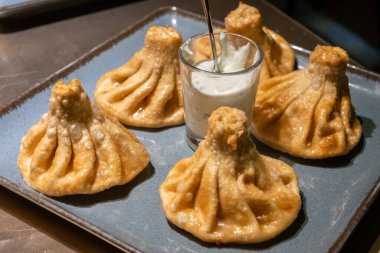 Bir tabak altın kızartılmış khinkali, geleneksel soslu Gürcü köftesi.