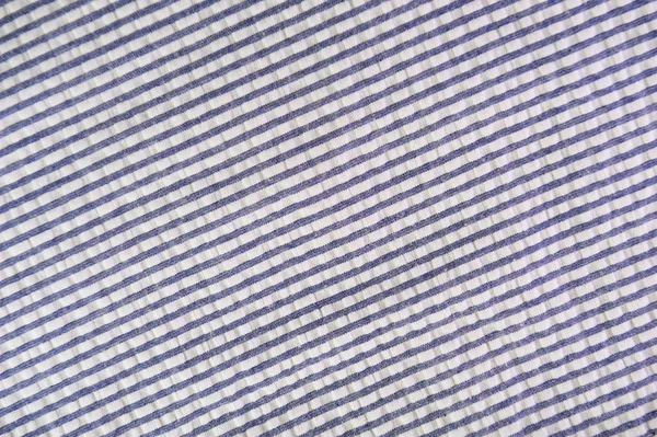 Close up on crumpled blue material texture fabric. Striped blue and white textile pattern as a background.