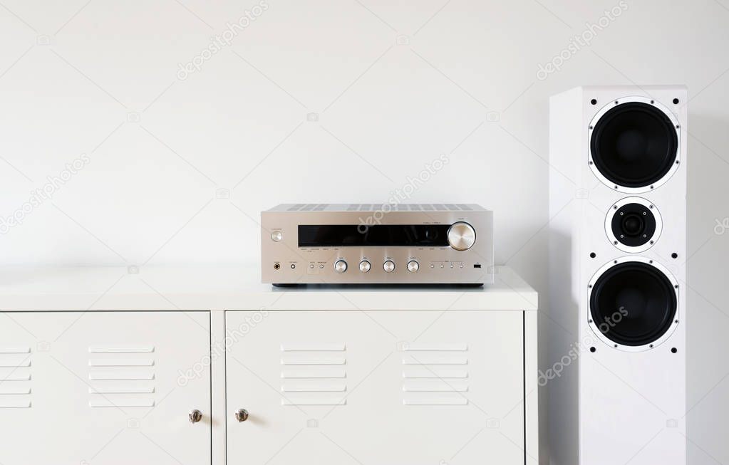 Modern audio stereo system with white speakers on bureau in modern interior