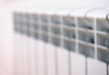 Bokeh arka plan çözünmüş beyaz ısıtma radyatörü. Beyaz radyatör. Isıtma radyatörü. Arka planda yeni ısıtma radyatörü var. Isıtıcı, ısı.