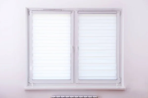 White roller blind on a metal plastic window