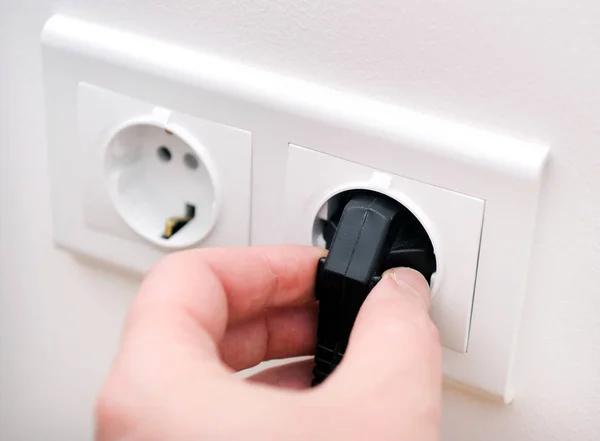 Male electrician inserting plug into socket in order to check its serviceability, closeup
