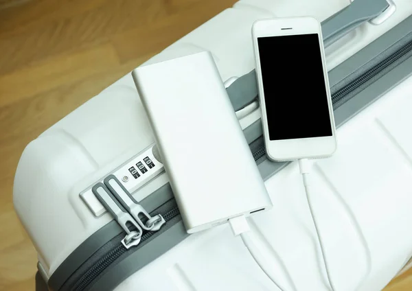 Bir cep telefonunu elektrik bankasıyla beyaz bir valizle şarj etmek.
