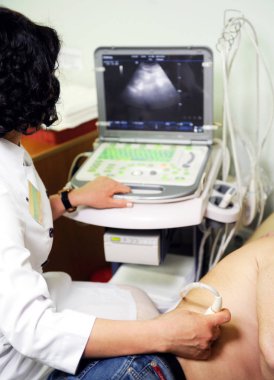 Doktor hasta için test yapmak için ultrason makinesi kullanıyor.