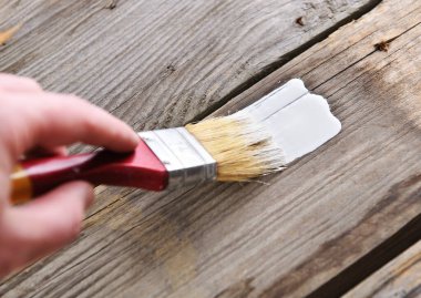 Adam eski ahşap tahtaları fırça ve boyalarla boyuyor, yakın plan.