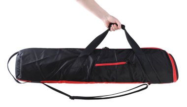 Erkek el, beyaz arka planda izole edilmiş silahlar için siyah yumuşak bir çanta tutuyor. Silah taşımak ve depolamak için çanta. Stüdyo ışıklarını taşımak için çanta taşıma.