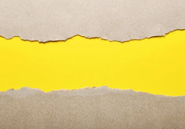 Dark paper with torn edges isolated on a yellow background of colored paper inside. Good paper texture
