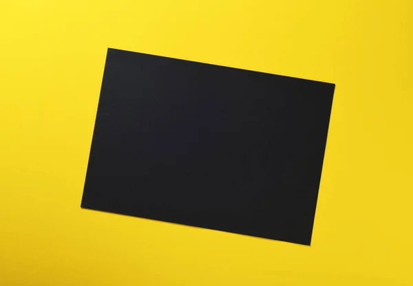 Una Hoja Papel Negro Sobre Fondo Amarillo —  Fotos de Stock