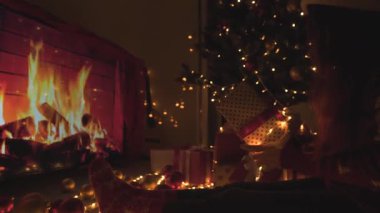 Parlak bir şömine, güzel dekore edilmiş bir Noel ağacı ve neşeli tatil atmosferinin sıcacık özünü mükemmel bir şekilde yansıtan bir dizi hediye içeren harika, sıcak bir sahne.