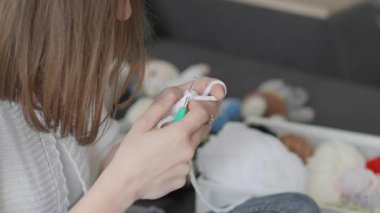 Yetenekli bir kadın beyaz iplikle örgü örme becerilerini sergiliyor, renkli doldurulmuş oyuncakların arasında karmaşık tasarımlar yapıyor, sanatın, yaratıcılığın özünü yakalıyor, ve iş başında zanaat yapmanın zevkini yaşıyor.