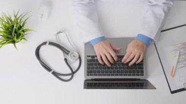 Steteskop ve hasta belgeleriyle çevrili bir dizüstü bilgisayardaki tıbbi profesyonel tipler, verimli dijital kayıt tutma odaklı modern bir sağlık ortamını vurguluyor.