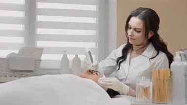 Yetenekli bir kozmetolog, modern bir klinikteki bir hastaya rahatlatıcı bir cilt bakımı uyguluyor, hassas teknikler sergiliyor ve dinlenmek ve gençleşmek için rahatlatıcı bir ortam yaratıyor.