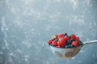 Kevgir içinde yıkanmış taze sulu çilek karışımı. Arka plan kopya alanı ile