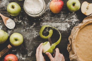 Yemek elma pasta. Elma elmalı turta için ahşap masa üzerinde peeling eller. Üstten görünüm.