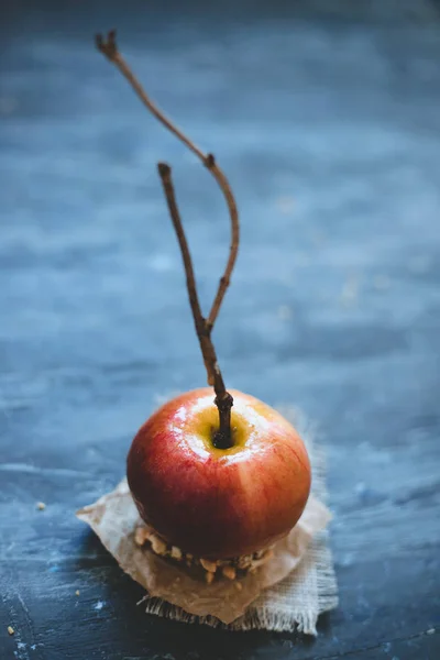 Old fashioned caramel apple with brunch sticks and nuts. Selective focus.