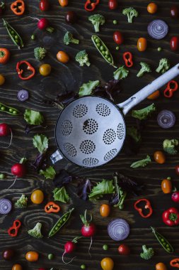 Taze organik sebze mutfak kevgir ile. Yeşil bezelye, brokoli, domates, turp ahşap masa üzerinde. Üstten görünüm.