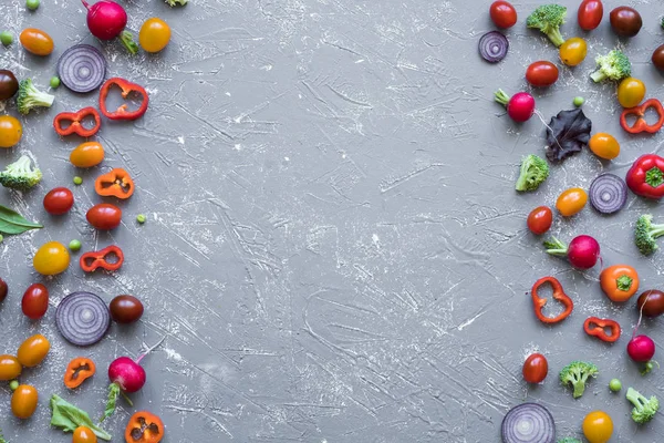 Çerçeve taze organik sebze. Turp, yeşil bezelye, brokoli, domates ve soğan ile kopya alanı gri arka plan üzerinde.