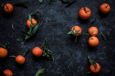 Taze mandalina veya dokulu koyu arka plan üzerinde yapraklarla mandarin portakal. Üstten görünüm.