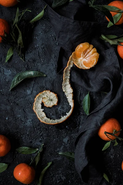 Soyulmuş mandarin portakal veya mandalina dokulu koyu arka plan üzerinde yaprakları ile. Üstten görünüm.