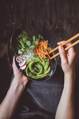 Pirinç Noodle, sebze ve ahşap arka plan üzerinde avokado ile kase taze vejetaryen yemek. Kopya alanı ile üstten görünüm