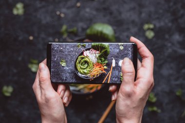 Gıda fotoğrafçılığı. Lezzetli sebze salatası smartphone ile resim çekmek eller