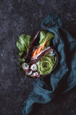 Vejetaryen Asya kase pirinç noodle, havuç, turp ve siyah arka plan üzerine salatalık. Üstten görünüm.