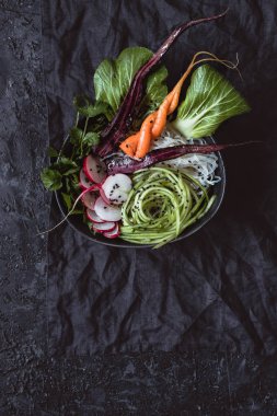 Vejetaryen Asya kase pirinç noodle, havuç, turp ve siyah arka plan üzerine salatalık. Üstten görünüm.