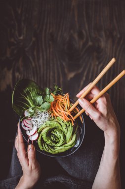 Pirinç Noodle, sebze ve ahşap arka plan üzerinde avokado ile kase taze vejetaryen yemek. Kopya alanı ile üstten görünüm