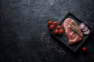 Domates, soğan ve biberiye siyah arka plan üstten görünüm üzerinde çiğ Dana kaburga eti. Kopya alanı ile.