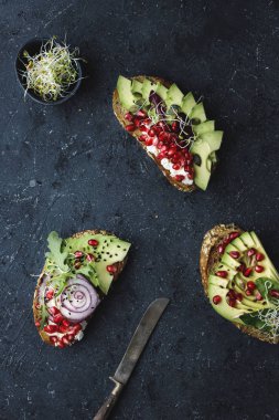Avokado dilimleri, tohum ve kopya alanı ile koyu arka plan üzerinde lahanası ile sağlıklı avokado sandviç.