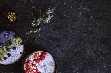 Hindistan cevizi yoğurt, meyve, çilek ve siyah arka plan üstten görünüm üzerinde Antep fıstığı ile sağlıklı güler yüzlü kase. Kopya alanı ile