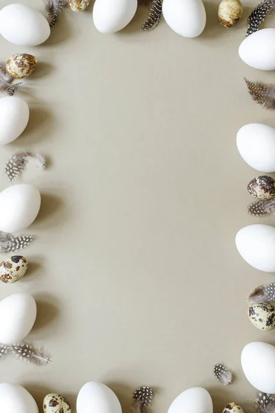 Easter background. Easter frame made of white eggs, quail eggs and feathers with copy space.