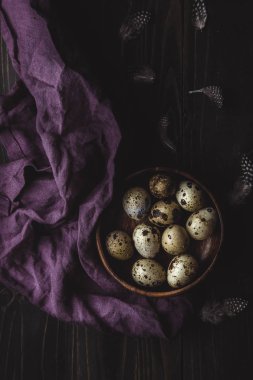 Bıldırcın yumurtası tüyleri koyu ahşap arka plan üzerinde ahşap kase.