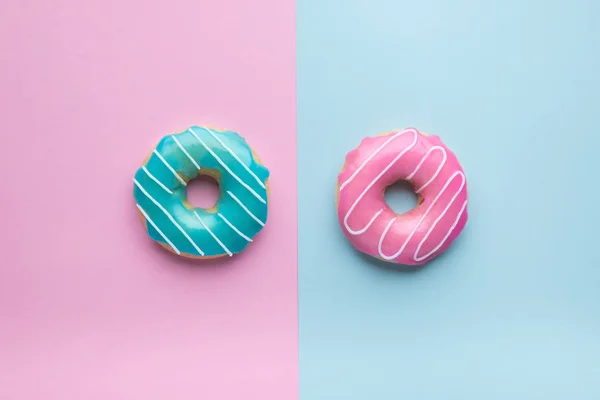 Donuts azuis e rosa sobre fundo rosa e azul . Imagens De Bancos De Imagens