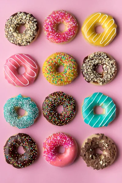 Colorful sweet background. Delicious glazed donuts on pink background.