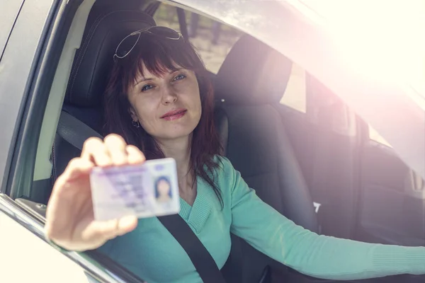 Getting a driver\'s license, a beautiful driving girl shows a new driver\'s license