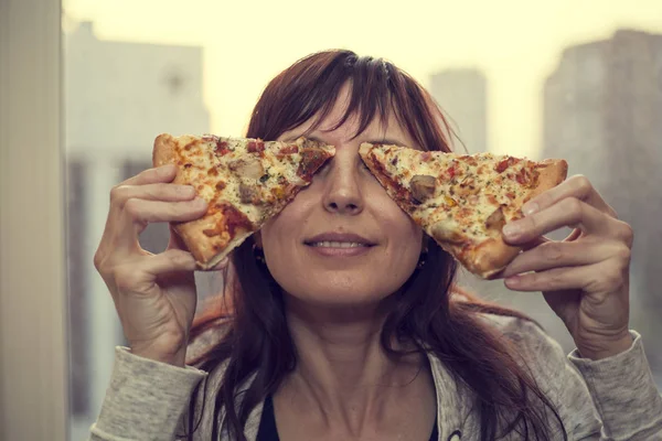 Order a pizza, the girl put a piece of triangular pizza to the eye, toned