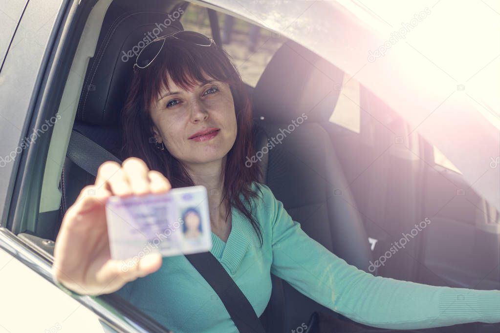 Getting a driver's license, a beautiful driving girl shows a new driver's license