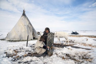 Nadym, Rusya Federasyonu - 27 Nisan 2018: tundra, açık alan, soğuk kış hava, Ulusal giysiler içinde çocuklar yardım Papa'nın yakacak odun, editoryal doğrayın