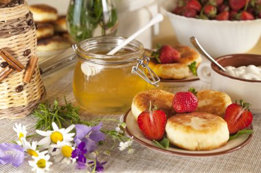 Kahvaltıda peynirli büyük bir tabak, süzme peynirli krep, taze çilekli krep ve papatya çiçekli çilek.