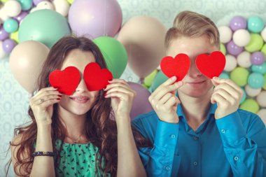 Genç, seven çift, birbirlerine öpücük, dudakları bir kalp şeklinde şeker ile kapak; Mutlu çift iki kağıt kalp tutan aşık