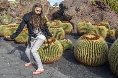 Lanzarote, Kanarya Adaları, İspanya; Guatiza Köyü, kız bahçede kaktüs kaktüs üzerinde oturur