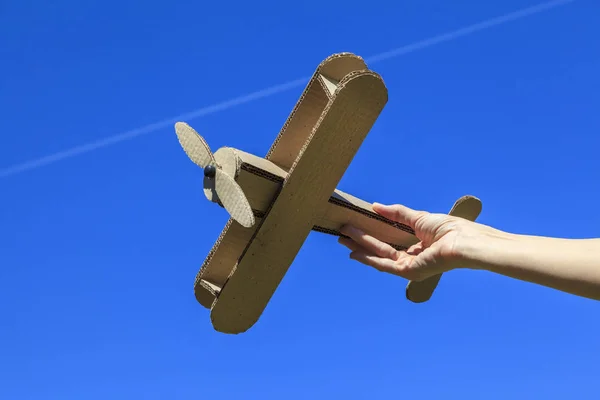 The concept of flight, a cardboard plane in hand, against the sky, a dream of rest, a time of discounts on goods, freedom