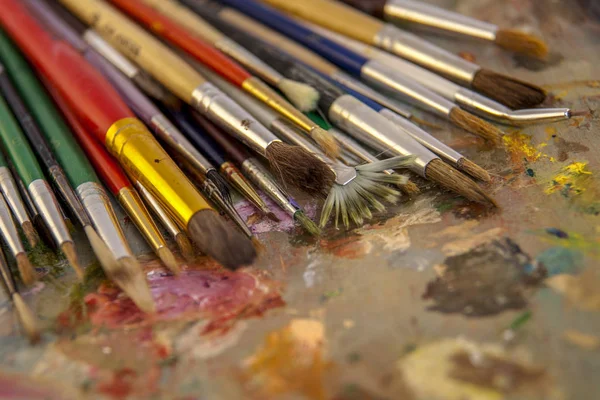 an artist\'s brush on the palette, artists brushes and oil paints on wooden palette.