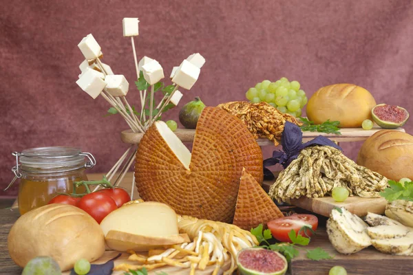 Smoked cheese pigtail, Traditional Polish smoked cheese, Chechil cheese on the Wood background. Smoked cheese    on a cutting board, whith grape, basil, figs, a large assortment of cheeses, closeup