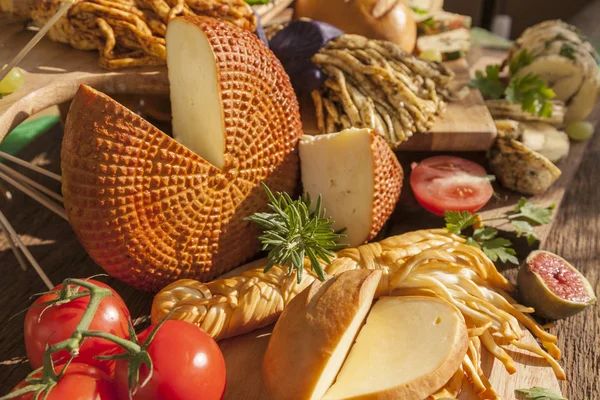 Smoked cheese pigtail, Traditional Polish smoked cheese, Chechil cheese on the Wood background. Smoked cheese    on a cutting board, whith grape, basil, figs, a large assortment of cheeses, closeup